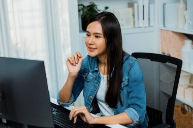 Genç ve güzel Asyalı yaratıcı yönetici bilgisayar üzerinde çalışıyor, yeni bir web sitesi tasarımı ile yeni sosyal medya çevrimiçi kanal planlaması üzerinde modern ev ofisinde kot pantolon gömleği ile çalışıyor. Taktik.