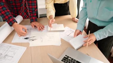 Mimarlık ve güvenlik mühendisi, modern ofiste doğruluk için mimari belge ve ölçüm aracı kullanılarak dizüstü bilgisayarın üzerinde sergilenen planlar hakkında tartıştı. - Yakın çekim. Tanımlama.