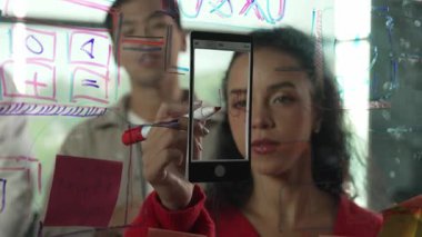 Cam duvarda yaratıcı fikirleri paylaşmak için renkli yapışkan notlar kullanarak pazarlama fikrini değerlendiren mutlu profesyonel iş adamları. Bir grup farklı iş adamları strateji hakkında tartışıyorlar. Yönlendirici.