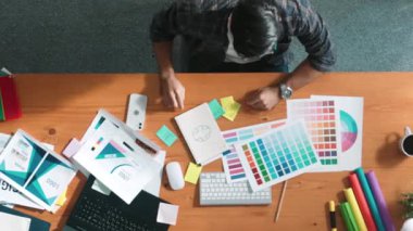 Kulaklıktan müzik dinlerken yetenekli iç dizayn grafiklerinin yukarıdan aşağı havadan görüntüsü. Proje yöneticisi kulaklıkla çalışırken ve rahat şarkılar dinlerken stüdyoda hareket ediyor. Sempozyum.