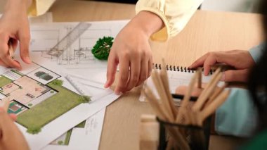 Mimarlar, mimari belgeleri ve ahşap blokları ofis çevresinde dağıtan çalışma arkadaşlarının desteğiyle bina planında ölçüm aracı ve kalem takibi kullanıyorlardı. - Yakın çekim. Tanımlama.