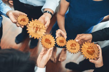 Bu resim, modern bir iş yerinde iş başarısını, verimliliği ve yenilikçi bağlantıları vurgulayarak, birbirine kenetlenmiş takım çalışmasını temsil eden çeşitli vitesleri tutan çeşitli elleri gösteriyor. Dostluk