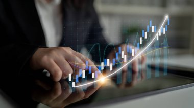 Bir iş adamı dijital tablet kullanarak finansal verileri analiz ediyor. Bir grafik, modern ofis ortamında imajı, eğilimleri ve büyümeyi gösteriyor. Etki