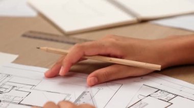 Akıllı mimar ya da akıllı mühendisin ölçüm aracı ve kalem el kullanarak mimari ofisindeki inşaat isabet planı üzerine detaylı bir yazı yazışının videosu. Eline odaklan. - Yakın çekim. Tanımlama.
