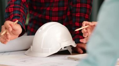 Mimarlık ve güvenlik mühendisi, modern ofiste dizüstü bilgisayarda mimari belge ve ahşap blokla sergilenen planlar hakkında tartıştı. - Yakın çekim. Tanımlama.