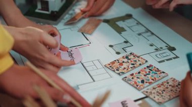 Dinamik bir iç tasarım planlama oturumu, kat planları ve renk örnekleriyle aktif olarak ilgilenen elleri, yaratıcılığı ve tasarım alanındaki işbirliğini yansıtıyor. SACTR