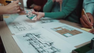 Mimari bir projede yer alan çeşitli bireylerden oluşan bir grup, profesyonel bir ortamda yaratıcı bir şekilde işbirliği yaparken planlar ve kat planlarını inceliyor. SACTR