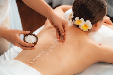 Lüks spa salonlarında sıcak mum ışığında cilt bakımı yaptıran kadın müşteri. Sağlık Spa vücut fırçasında tuz temizleme güzellik tedavisi. Sessiz.