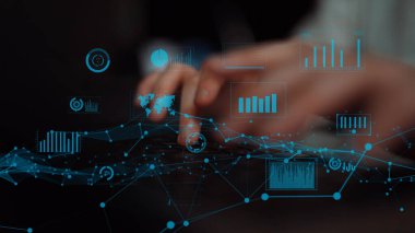 Dijital veri görselleştirme elementleriyle klavyeye yazı yazan ellerin yakın görüntüsü, finansal analiz ve teknolojik içgörüler için grafikler ve grafikler gösteriliyor. Xenic