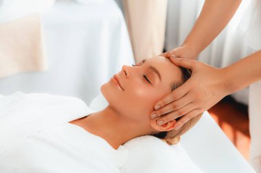 Kafkasyalı kadın stres önleyici kafa masajından ve lüks tatil beldesi ya da otel spa salonundaki modern ışık ortamında yüz güzelliği eğlencelerini şımartmaktan hoşlanıyor. Sessiz.