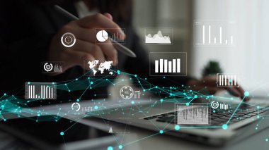 Bir iş adamı, çağdaş ofis ortamında modern analitik teknikler sergileyerek bir dizüstü bilgisayarda çeşitli dijital grafik ve çizelgelerle ilgilenir. Xenic
