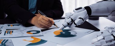 Bir insan el yazısı, teknolojinin iş uygulamalarına entegrasyonunu ve bunun takım çalışması ve verimliliği üzerindeki etkisini yansıtan robotik bir elin yanında notlar da yazar.