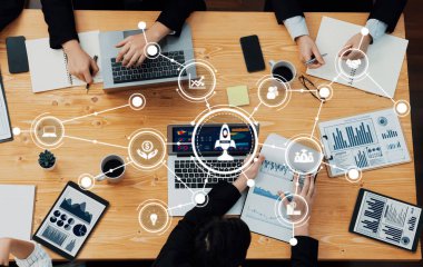 Modern bir çalışma alanında dinamik bir iş toplantısı gerçekleşiyor. Ekip üyeleri veri grafikleri ve görselleri incelerken, işbirliği ve yenilik sergilerken tartışmalara dalıyorlar. Dostluk