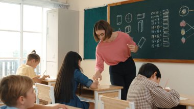 Zeki öğretmen sınıfta fikri açıklarken sevimli öğrenci ödevlerini kontrol ediyor. Not defterine bakıp matematik teorisinden çocuğa bahsederken sınıfta dolaşan çekici bir eğitmen. Pedagoji.