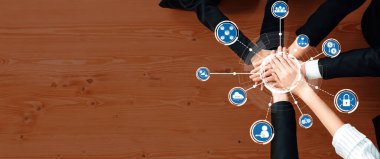 Bu resim, yenilikçi fikirleri temsil eden dijital simgelerle tamamlanmış takım çalışmasını ve işbirliğini sembolize eden bir iş toplantısında bir grup elin bir araya geldiğini gösteriyor. Dostluk