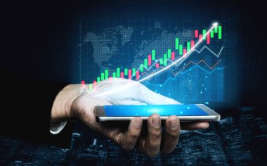 Finansal tabloları gösteren bir akıllı telefonu tutan bir elin yakın plan görüntüsü ve büyümeyi ve finans alanındaki yeniliği sembolize eden karanlık bir arkaplana karşı yükselen bir grafik. Etki