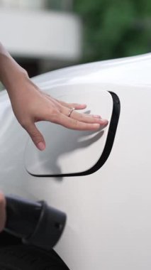 İlerici kadın evdeki elektrikli aracına şarj istasyonu fişi takıyor. EV otomobilleri çevreye yararlı temiz ve yeşil enerji kavramı sağlar.