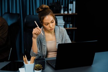 Modern ofiste gece geç saatlerde arka tarafta çalışan iş arkadaşı ile birlikte veri analizi sosyal medya çevrimiçi proje işini rapor etmek için bilgisayara odaklanan iş kadınının ciddi yüzü. İnfobahn.