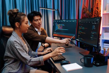 Bilgi teknolojisi geliştiricileri modern ofisteki neon ışık odasında verileri çevrimiçi olarak çalıştıran akıllı web sitesi geliştirme kodlayıcı sistemine işaret ediyorlar. İnfobahn.