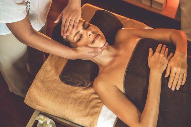 Beyaz kadın stres önleyici kafa masajı yapmaktan ve lüks otel veya otelde sıcak mum ışığında yüz güzelliği eğlencesi yapmaktan zevk alıyor. Sessiz.