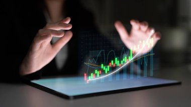 Profesyonel bir iş adamı dijital bir finans şemasını gösteren ve finans piyasası ve veri analizindeki büyüme ve başarıyı sembolize eden bir tabletin üzerinde asılı duruyor. Etki