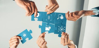 Bu görüntü, modern bir iş ortamında güvenlik çözümleri ve işbirliğini sembolize ederek bir bulmacayı tamamlayan ellerin yer aldığı dinamik bir takım çalışması sahnesini yakalar. Dostluk