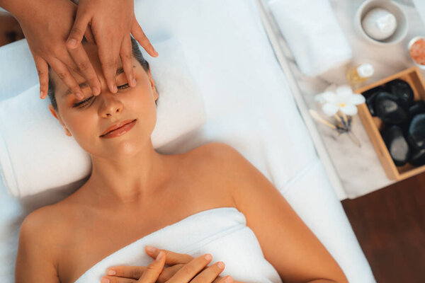 Panorama top view of woman enjoying relaxing anti-stress head massage and pampering facial beauty skin recreation leisure in dayspa modern light ambient at luxury resort or hotel spa salon. Quiescent
