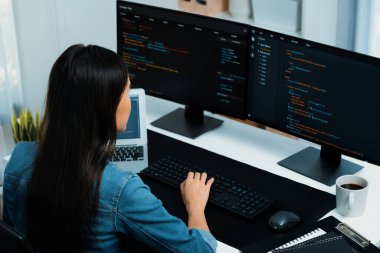 İnternet sitesi uygulamasının kodlama verileriyle birlikte online bilgi yazarak kot gömlek giyen genç Asyalı geliştirici. Güvenlik analizi ile çevrili iki ekran. Taktik.