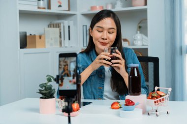 Gülümseyen, güzel Asyalı genç, lezzetli karışık çilek ve kiraz suyu detoksu içeceklerini inceleyen, sosyal medyada özel promosyon satışı için sağlıklı ürünler sergileyen. Taktik.