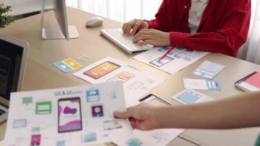 Mobil uygulama için kullanıcı arayüzü prototipini ofis çalışanlarına sunan harika bir şirket çalışanı. UX UI tasarımcısı kağıt üzerinde simge tasarımının işlevini açıklıyor. Sinerjik