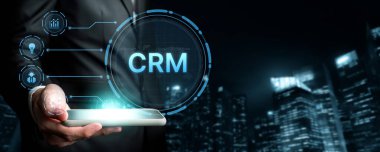 Bir iş adamı, CRM teknolojisini gece modern şehir siluetine karşı sergileyen bir tabletle ayakta duruyor. Müşteri ilişkileri yönetimi ve iş büyümesini sembolize ediyor. XDMCP