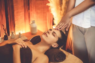 Beyaz kadın stres önleyici kafa masajı yapmaktan ve lüks otel veya otelde sıcak mum ışığında yüz güzelliği eğlencesi yapmaktan zevk alıyor. Sessiz.