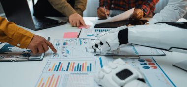 Bir robot kolu, modern bir şirket ortamında karar verme mekanizmasını geliştirmek için bir iş toplantısında takım üyeleriyle işbirliği yapar, grafikleri ve grafikleri analiz eder.