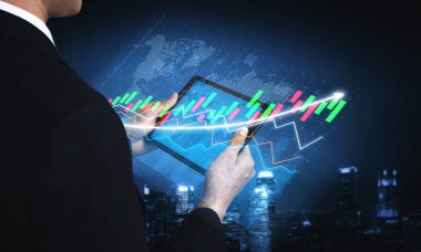 Bir işadamı, canlı borsa grafikleri aracılığıyla betimlenen finansal verileri analiz etmek için dijital tablet kullanarak geceleri şehrin ufuk çizgisinin önünde duruyor. Etki