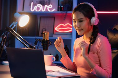 Geceleri podcast 'te olumlu konuşmalar yapan, pembe neon ışıklı modern stüdyoda sunum için dizüstü bilgisayar kullanan, gülümseyen, genç, güzel Asyalı bir etkileyiciydi. Taktik.