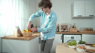 Mutlu baba yemek pişirirken müziğe geçiyor ve modern mutfakta öğle yemeği hazırlıyor. Aktif baba, sebze ve mutfak gereçleri ile çevrili sağlıklı yemek ya da salata yaparken şarkıyla dans ediyor. Pedagoji.