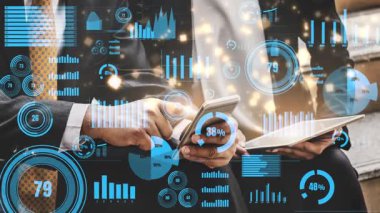 Mobil cihazlar, dinamik grafikler ve istatistiklerle çevrili dijital verilerle uğraşan iki iş adamı, şirket ortamında takım çalışmasını ve yeniliği sembolize ediyor. Xenic