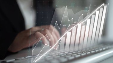 Bir klavyede iş dünyasından profesyonel tipler çalışırken, grafikte yer alan grafikte finansal büyüme ve performans eğilimleri modern bir ofisteki yatırım başarısını sembolize ediyor. Copula