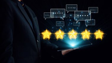 Bir iş adamı, üzerinde beş yıldız bulunan ve müşteri geribildirimi ve dijital çağdaki memnuniyetini gösteren bir tablet tutuyor. Dörtgen