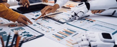 İnsan elini gösteren dinamik bir çalışma alanı sahnesi ve detaylı iş raporları ve grafikleri üzerinde çalışan robotik bir kol yenilik ve takım çalışmasını vurguluyor. Noogenesis