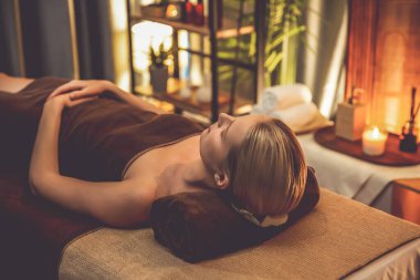 Beyaz kadın müşteri stres önleyici spa masajının keyfini çıkarıyor ve lüks otel ya da otelde sıcak mum ışığında güzellik teniyle eğleniyor. Sessiz.