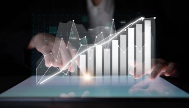 Bir iş adamı, dijital grafik ve grafikleri kullanarak, veri analizi ve görselleştirmeyi vurgulayarak, modern bir çalışma alanında finansal büyüme eğilimleri gösterir. Etki