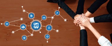 Takım çalışmasının ve yönetimin dinamik bir temsili, çeşitli ellerin ahşap bir masanın üzerinde bir araya gelmesi, işbirliğini ve etkili proje stratejilerini sembolize ediyor. Dostluk