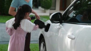 Evde şarj edilen elektrikli bir araçla okuldan yeni dönen anne ve kızın ilerici yaşam tarzı. Elektrikli araç, sürdürülebilir temiz enerjiyle çalışıyor..