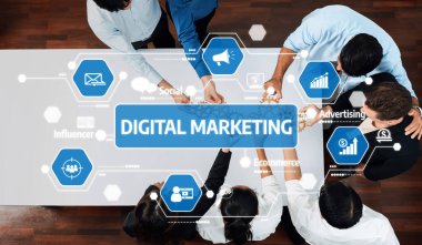 Çeşitli bir ekip modern bir ofiste dijital pazarlama stratejisi üzerinde işbirliği yapıyor. Görüntü, sosyal medya ve reklam gibi kavramları yakalıyor, takım çalışmasını ve yenilikleri vurguluyor. Dostluk