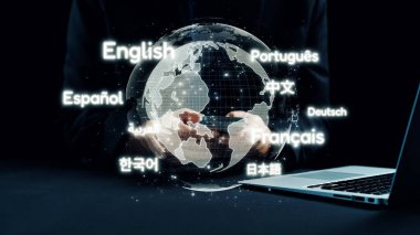 Modern bir çalışma alanında küresel iletişim ve çeşitliliği temsil eden, çeşitli dillerle çevrelenmiş, el ele tutuşan, dünyayı gösteren dijital bir tasvir. Dörtgen