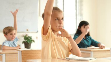 Ciddi öğrenci sınıfta otururken soruyu cevaplamak için elini kaldırdı. Sınıfta birlikte çalışırken günlük giysiler içindeki çok kültürlü çocuklar derse katılıyorlar. Çok basit. Pedagoji.