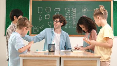 Zeki öğretmen, çeşitli çocuklar sınıf çalışması yapmak için birlikte çalışırken farklı çocukların zihin haritası çizdiği fikri açıklıyor. Çekici eğitmen öğretmek ve çalışmak hakkında konuşmak. Pedagoji.