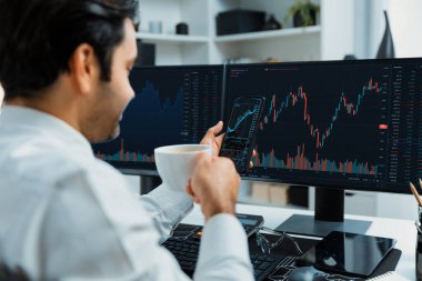 Elinde telefon dinamiğine odaklanan kahve fincanı tutan borsa yatırım ekranı veri analizini karşılaştırarak iç işlerinde yüksek kârlı finans teknolojisi pazarına yatırım yapıyor. Tahmin et..