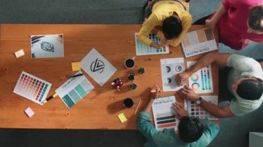 Proje yöneticisi renk paletleri seçerken tasarımcının tablete baktığı yukarıdan aşağıya hava görüntüsü. Profesyonel grafik tasarımının en üst görüntüsü ve logoya bakın. Yetenekli ekip grafikleri seçiyor. Sempozyum.